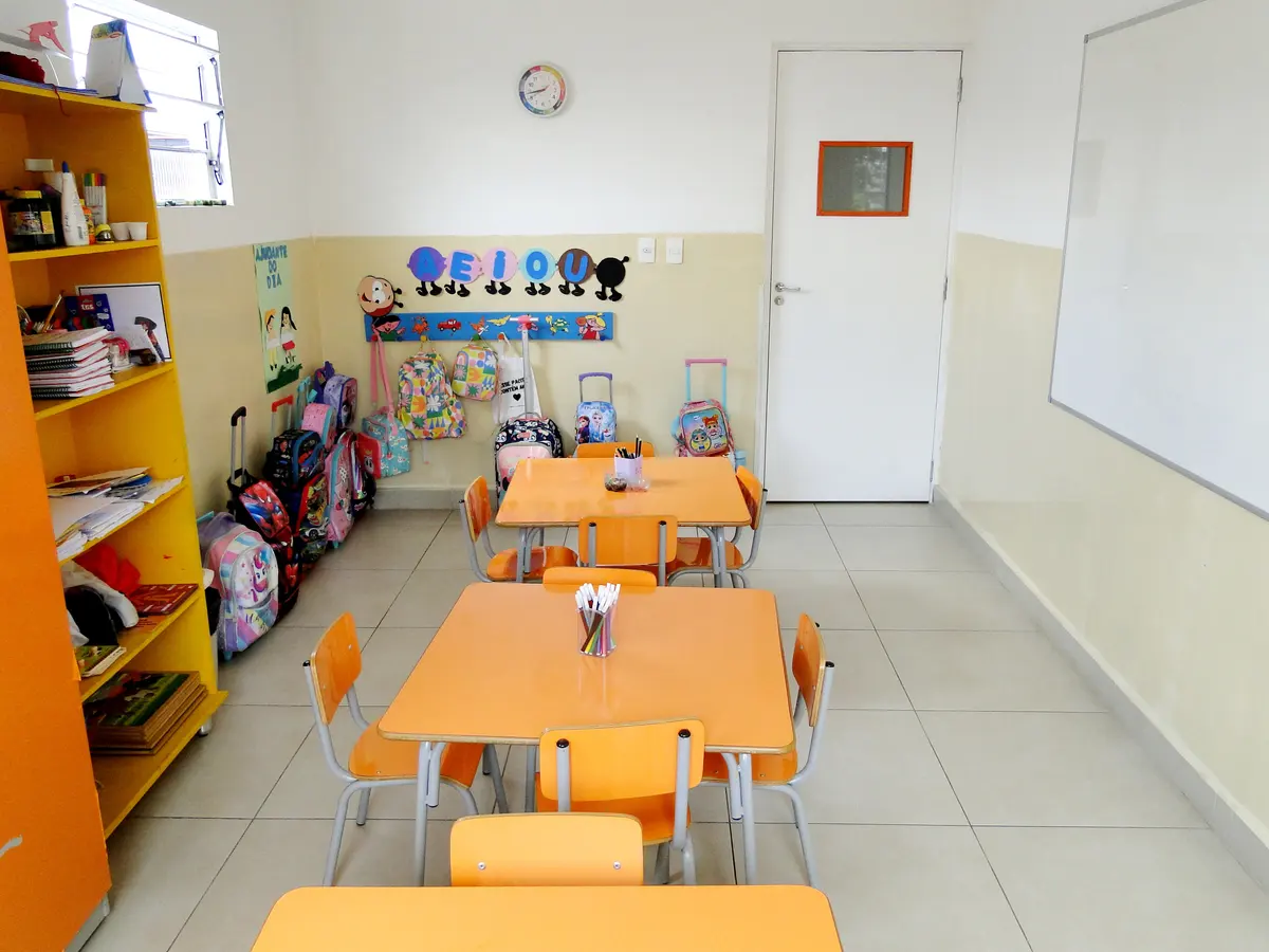 Sala da educação infantil com mesas redondas e cadeirinhas